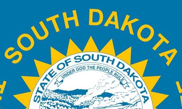 Detail of a light blue flag with the South Dakota state seal encircled by triangular sun rays and an inscription in gold