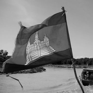 A black-and-white photograph of the Cambodian flag flying from a boat